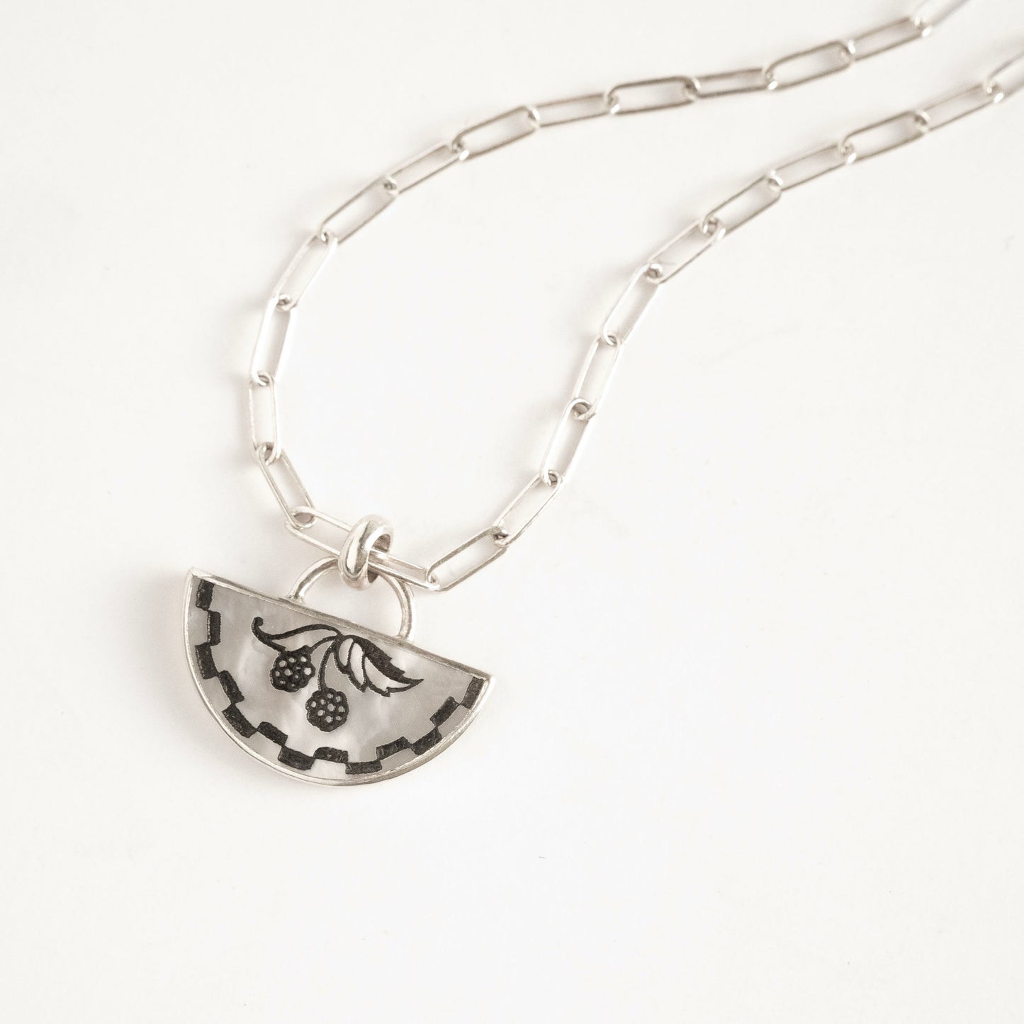 half moon mother of pearl pendant, etched with blackberry design., on silver chain.