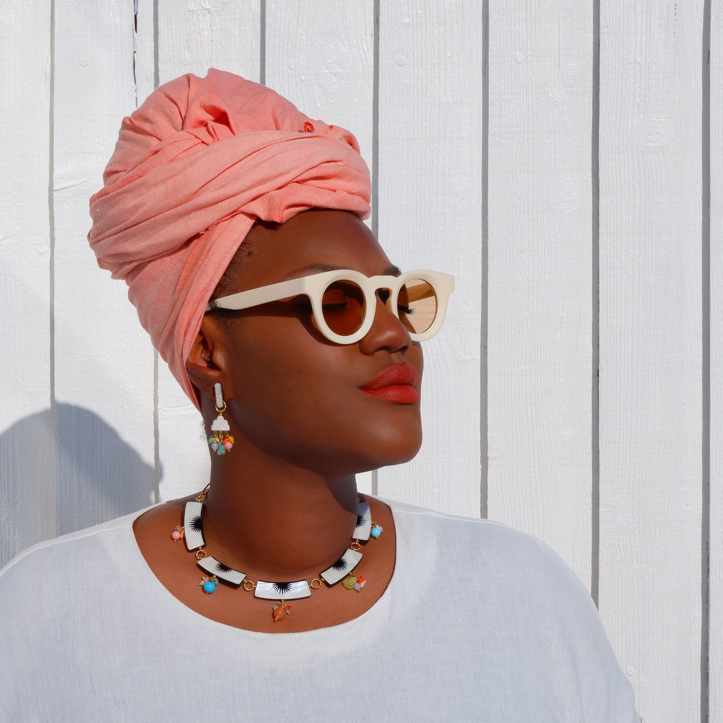 model, wearing mother if pearl collar necklace & mother of pearl deco style cloud-like  drop earrings with rainbow bead clluster