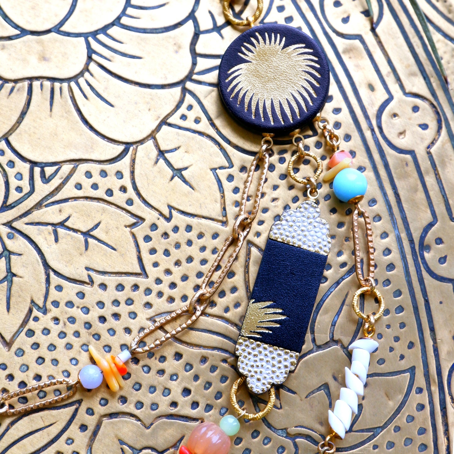 multi strand beaded chain necklace with palm-print black leather pieces close crop
