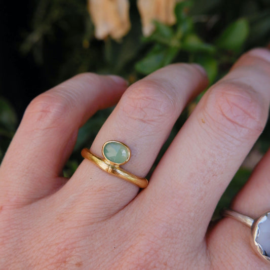 gold bamboo style ring with a small faceted oval pale apple green Chrysoprase gem stone, on a hand
