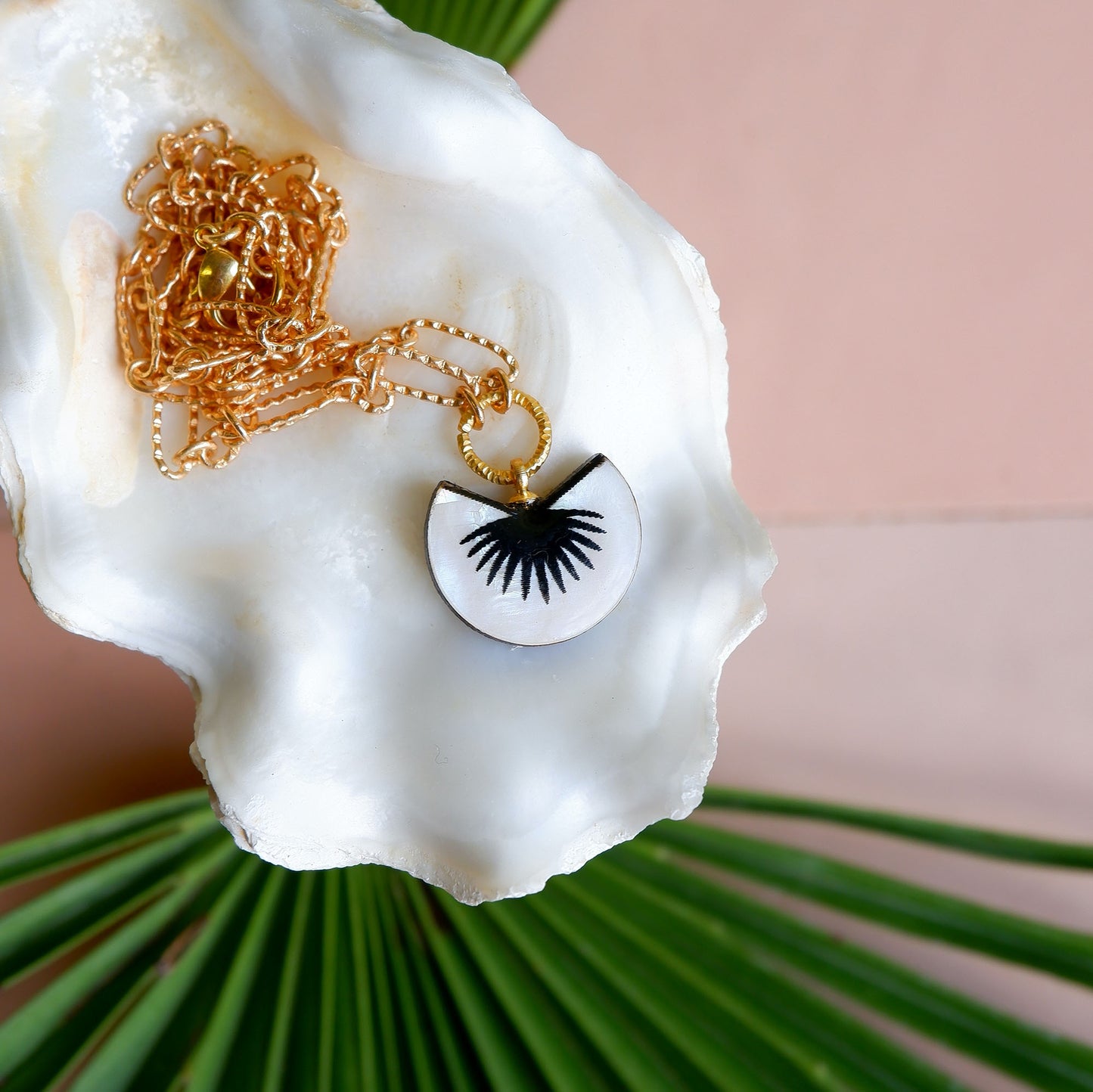 Black & mother of pearl graphic palm design pendant of golden chain, on an oyster shell
