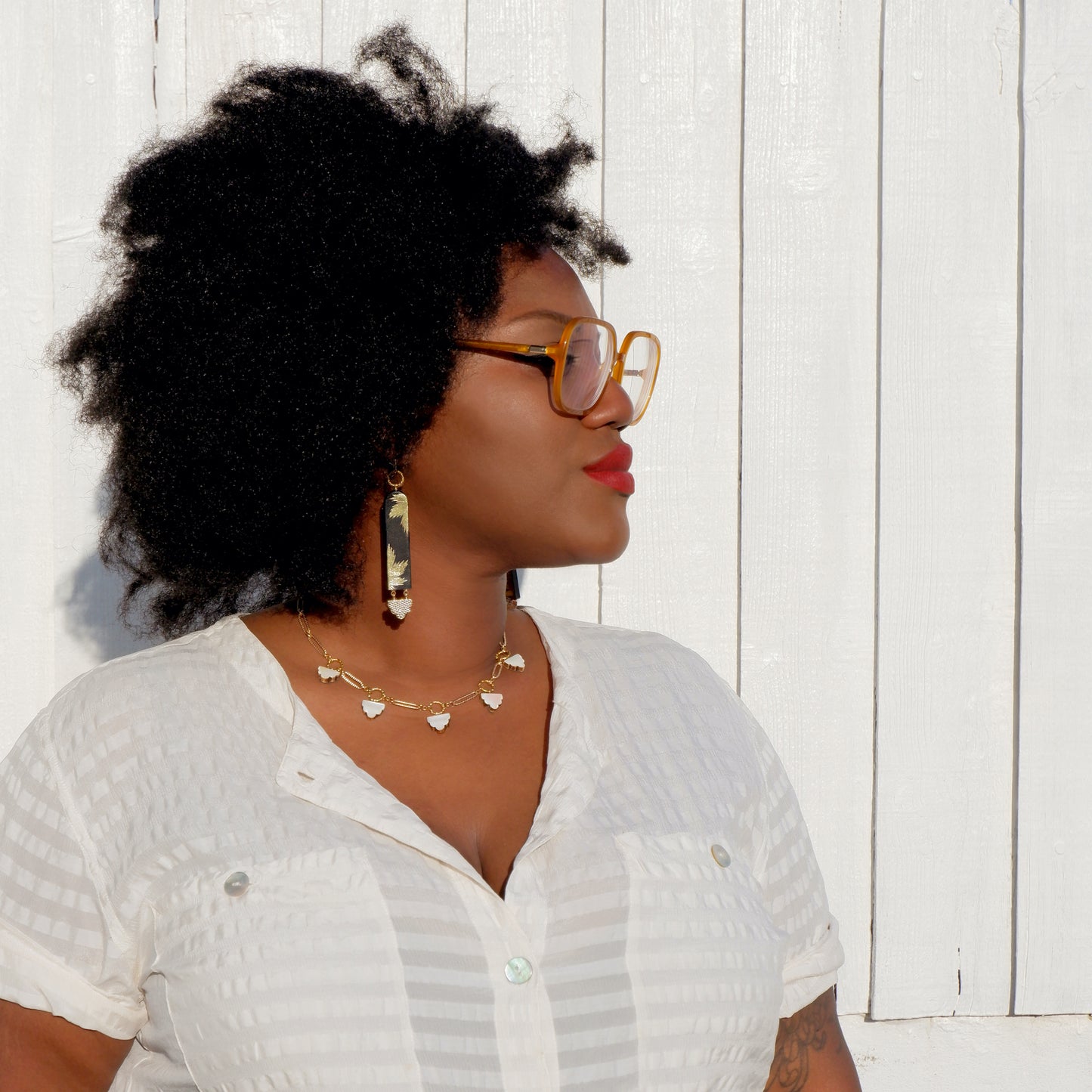 long drop hook earrings - arched strips in black leather, printed with gold palm trees, on model