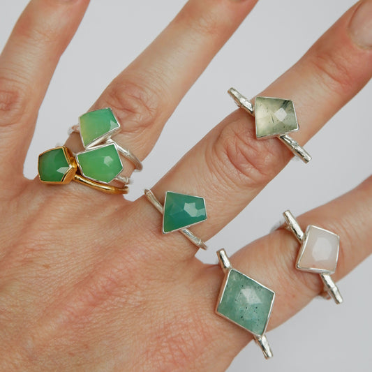 a stack of Sterling Silver and gold vermeil bamboo style rings with irregular angular geometric Chrysoprase gem stones in different shades of green, and pink, on a hand, against a white background