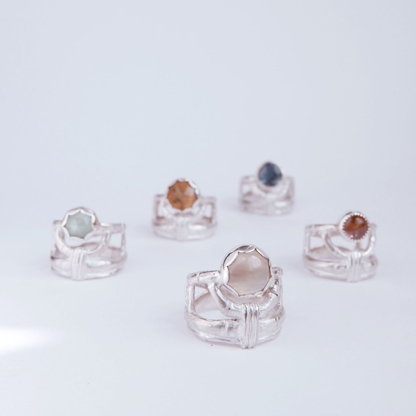 A group of 5 structural open-work ring in a bamboo style, each featuring a different round gemstone. Sterling Silver.