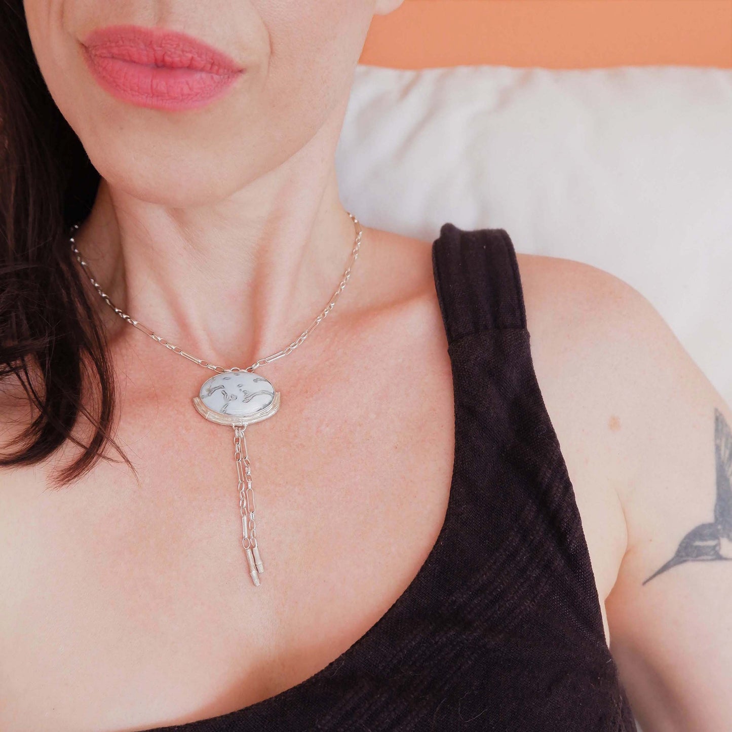Silver Lariat style chain necklace, with a large marbled pale sky blue peruvian opal pendant, framed by a hlaf halo of silver bamboo. On model.