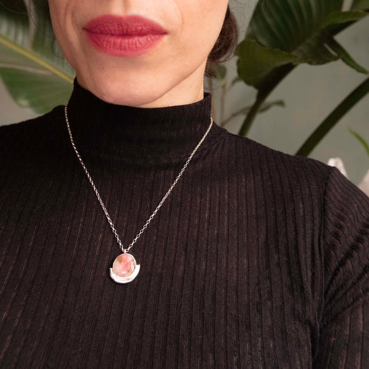 pink Opal gemstone circle pendant, framed by a silver bamboo style half moon halo mount, on a fine silver chain. On Model with black turtleneck top.