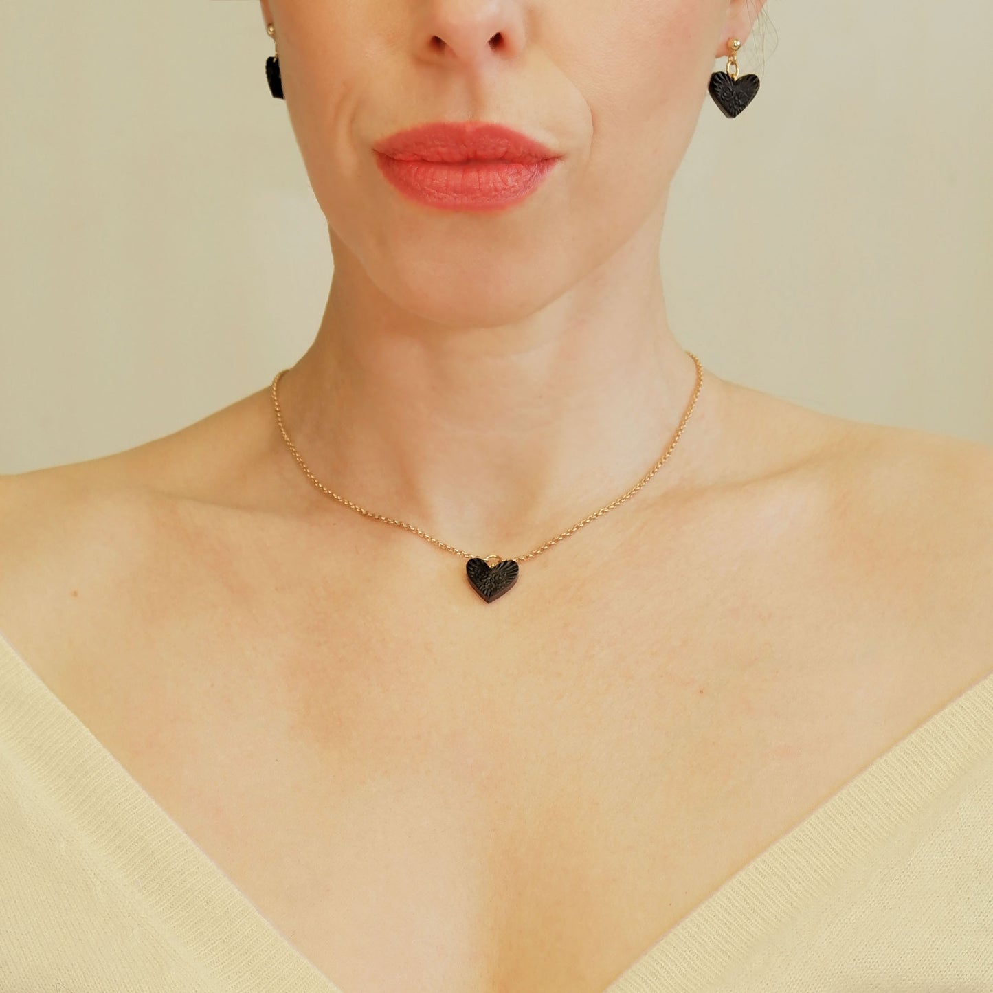 small Black Leather Heart pendant; embossed with a rose & rays design, on fine gold-plated belcher chain, on model, with matching black heart earrings