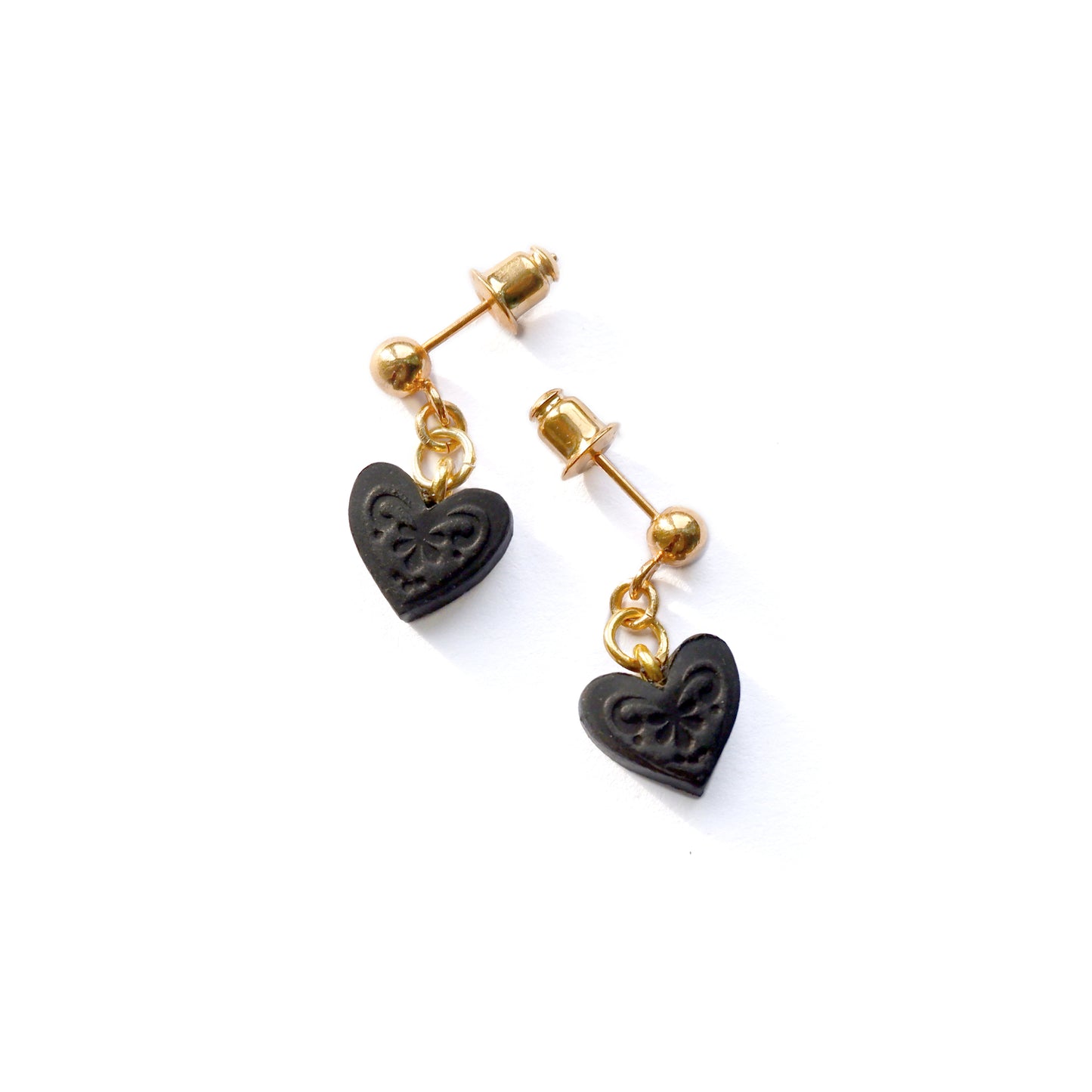 Gold ball stud earrings, with small black, embossed leather heart pendants.
