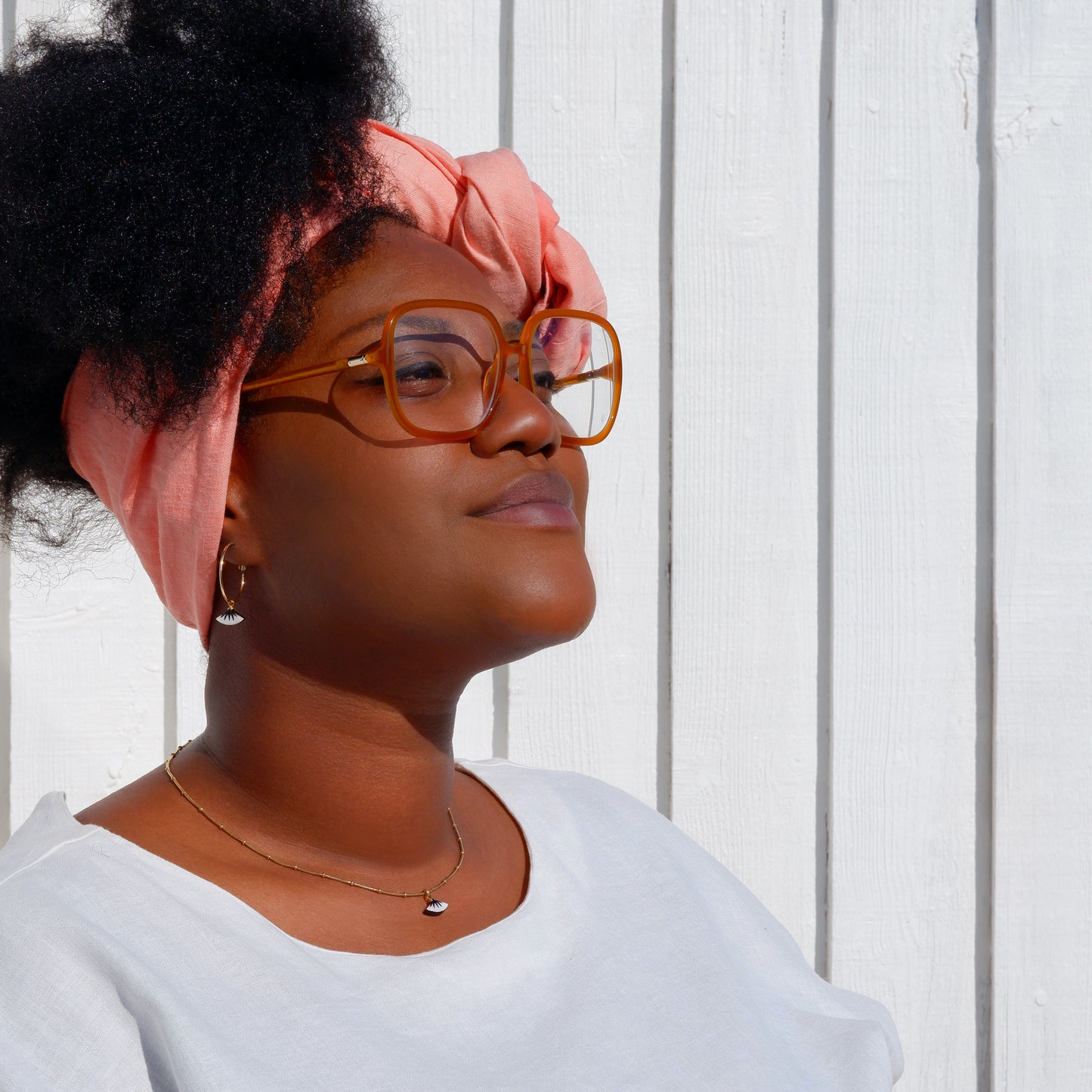 small gold hoop earrings with black spiky palm design on mother of pearl, on model