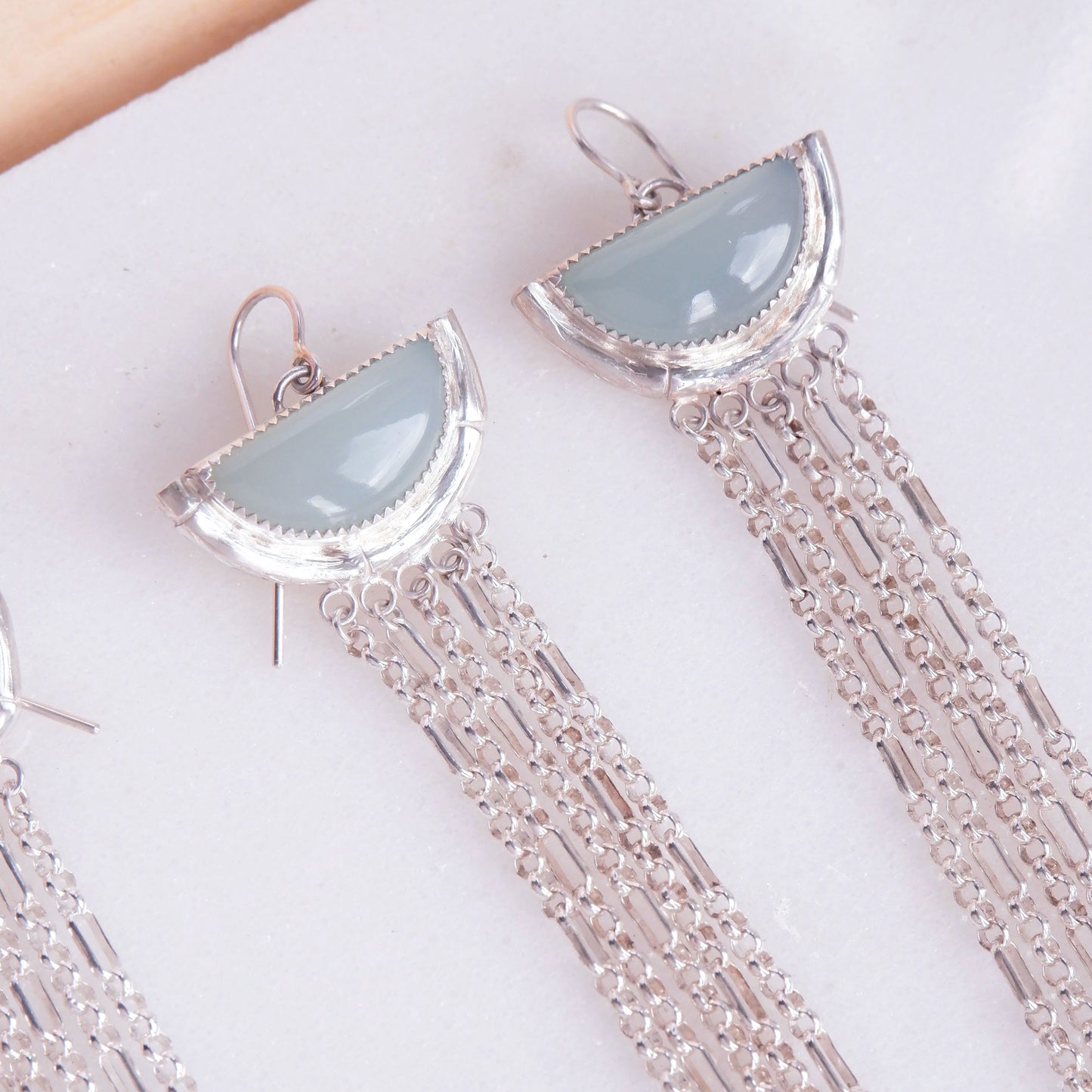 dramatic long chain fringe chandelier tassel earrings with half moon shaped semi precious aqua blue chalcedony gemstones,  cupped by solid silver bamboo hammock, with simple silver wire hooks. Close up cropped shot.