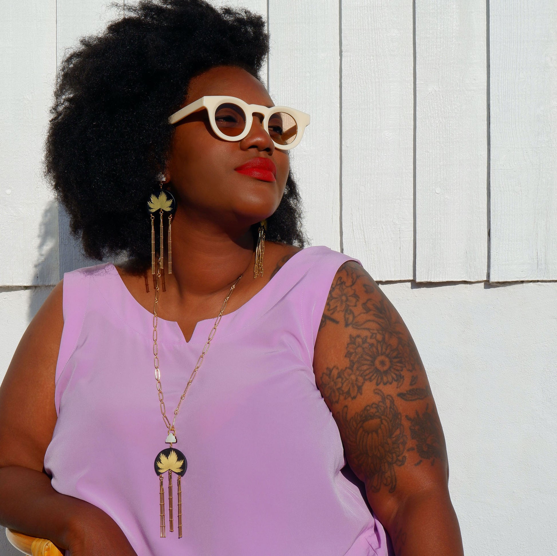 leather medallion pendant, with gold palm tree print,  long gold chain tassels, and mother of pearl cloud, on long-link gold chain, with matching earrings, on model