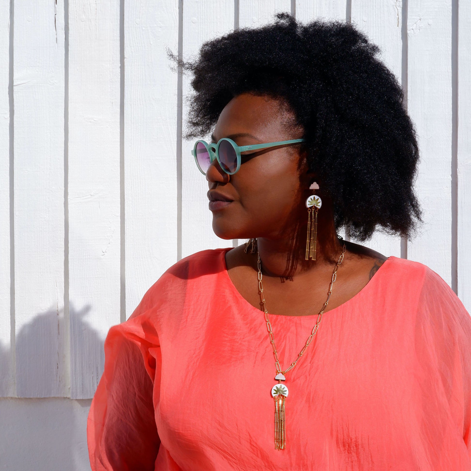 leather medallion pendant, with gold palm tree print,  long gold chain tassels, and mother of pearl cloud, on long-link gold chain, with matching earrings, on model