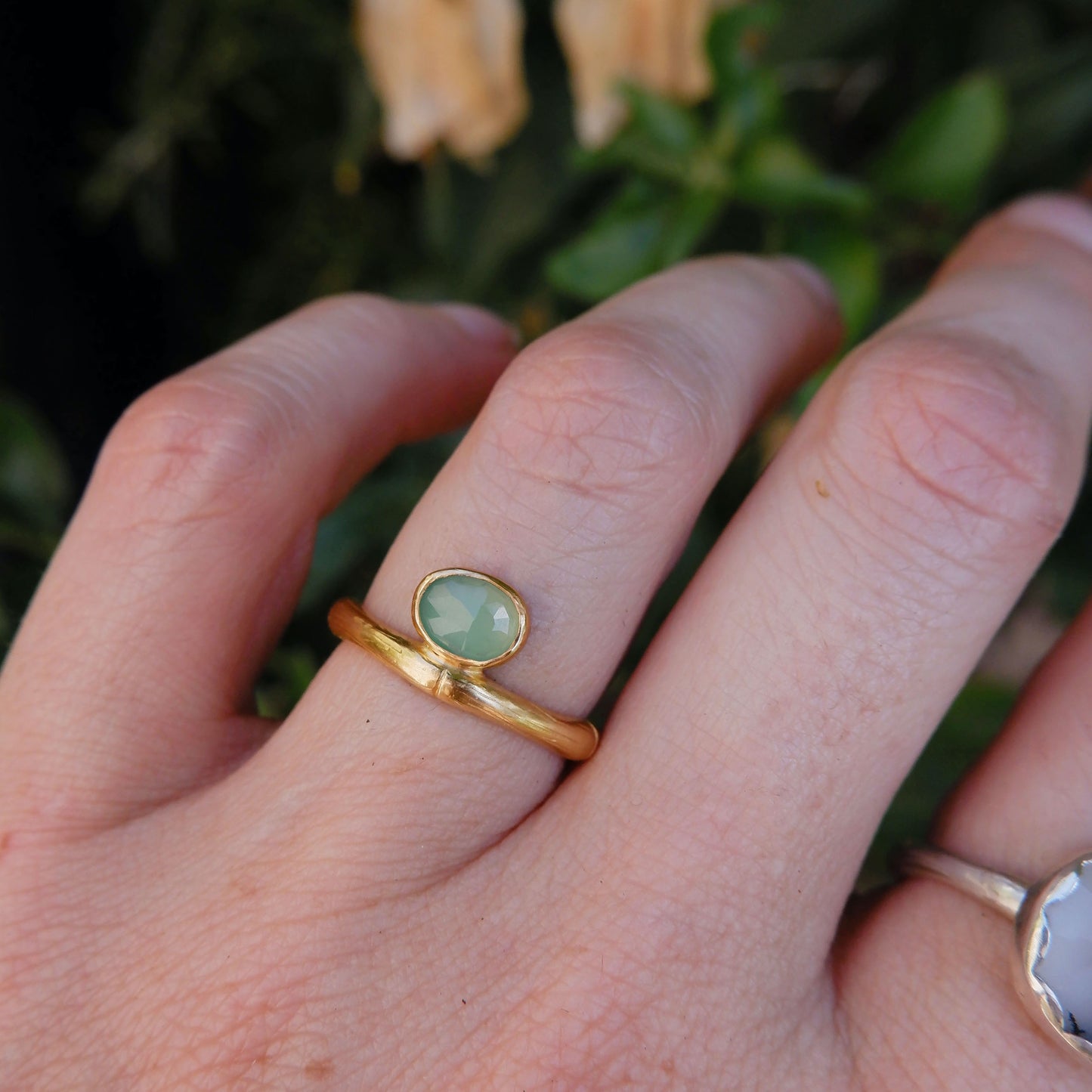 gold bamboo style ring with a small faceted oval pale apple green Chrysoprase gem stone, on a hand