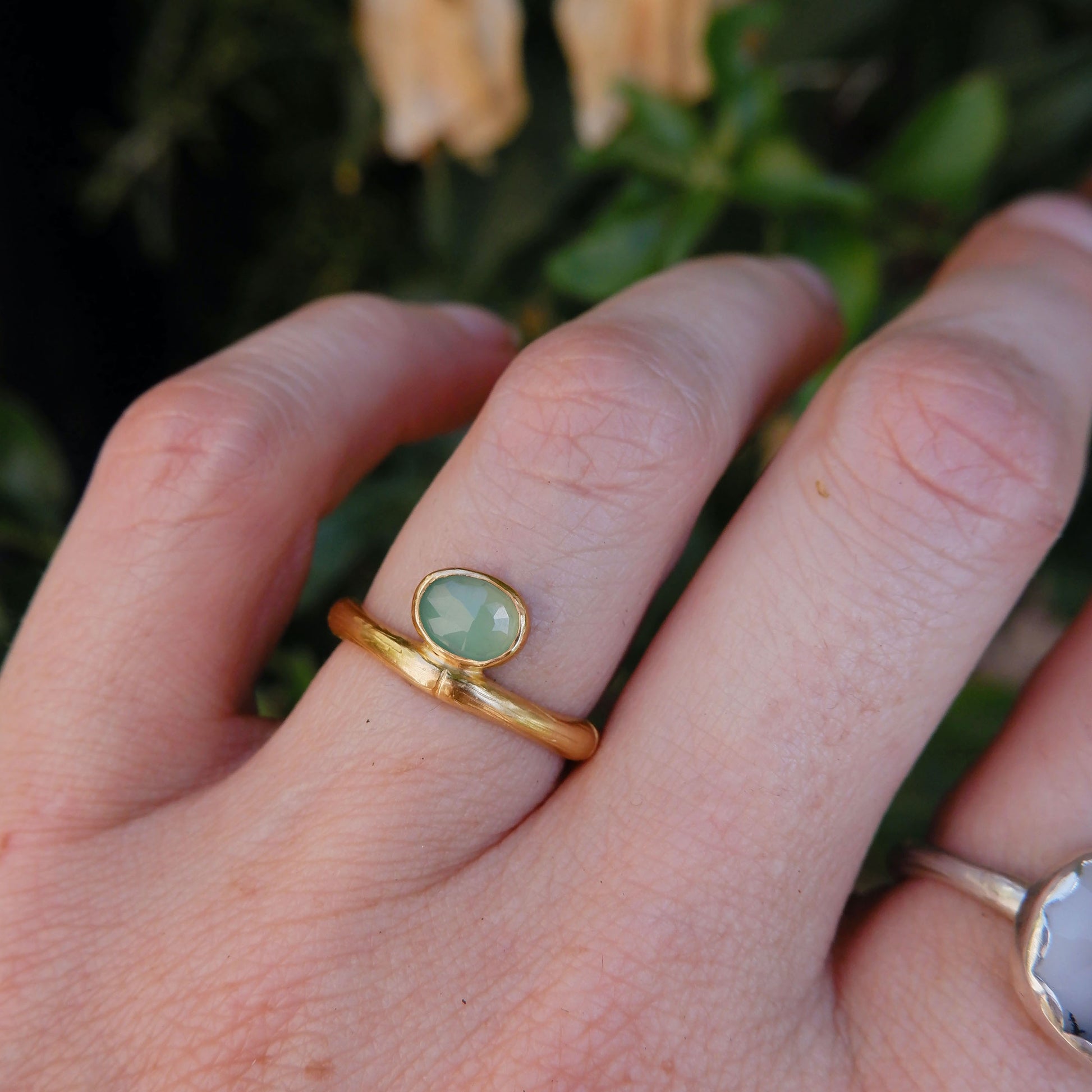 gold bamboo style ring with a small faceted oval pale apple green Chrysoprase gem stone, on a hand