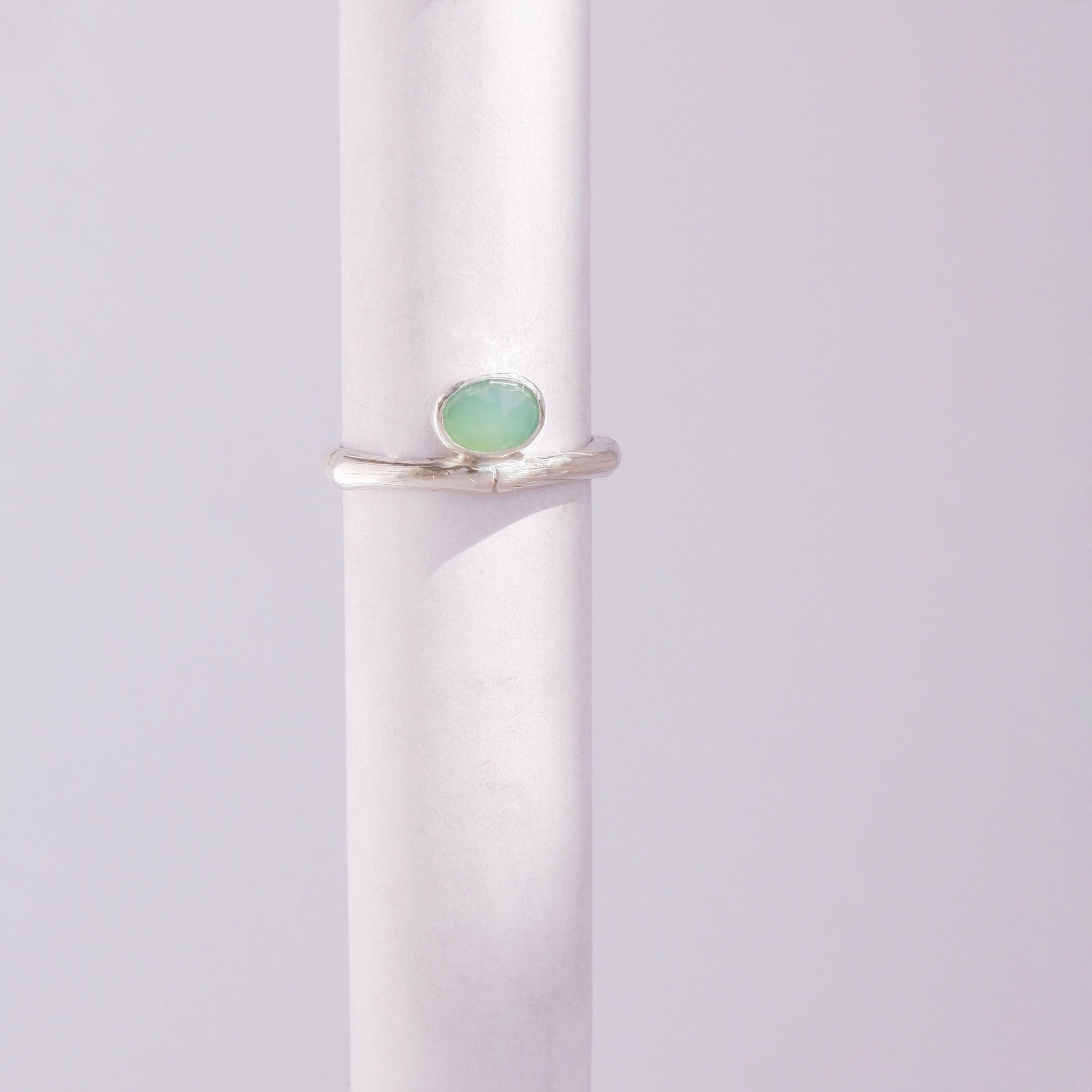 Sterling Silver bamboo style ring with a small oval pale apple green Chrysoprase gem stone, on a white background