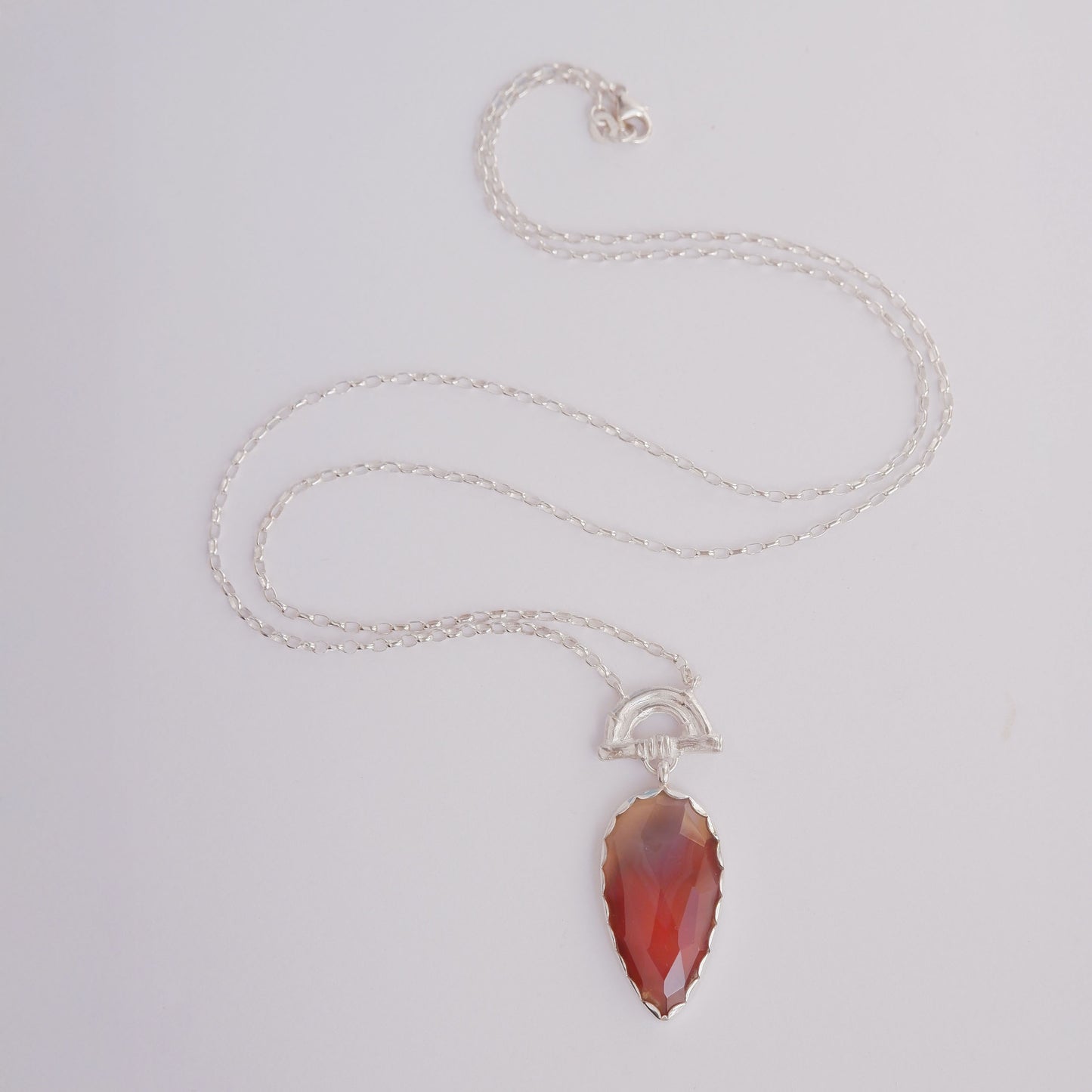 Pendant with long Pear-shaped faceted marbled red Botswana agate Gemstone hanging from silver Bamboo Arch, on fine silver chain.