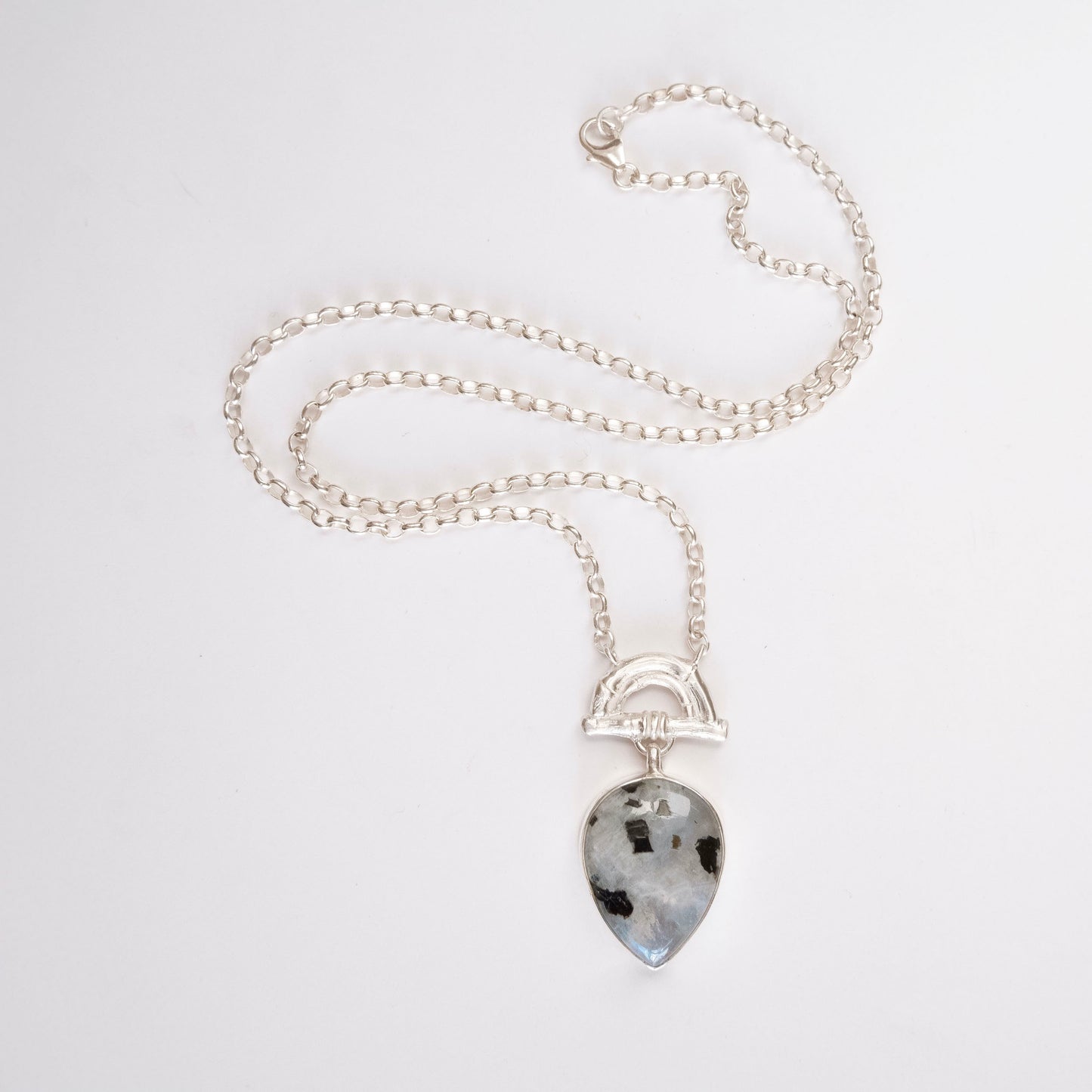 Pendant with  pear-shaped pale Tourmalated Moonstone Gemstone hanging from silver Bamboo Arch, on fine silver chain. white background