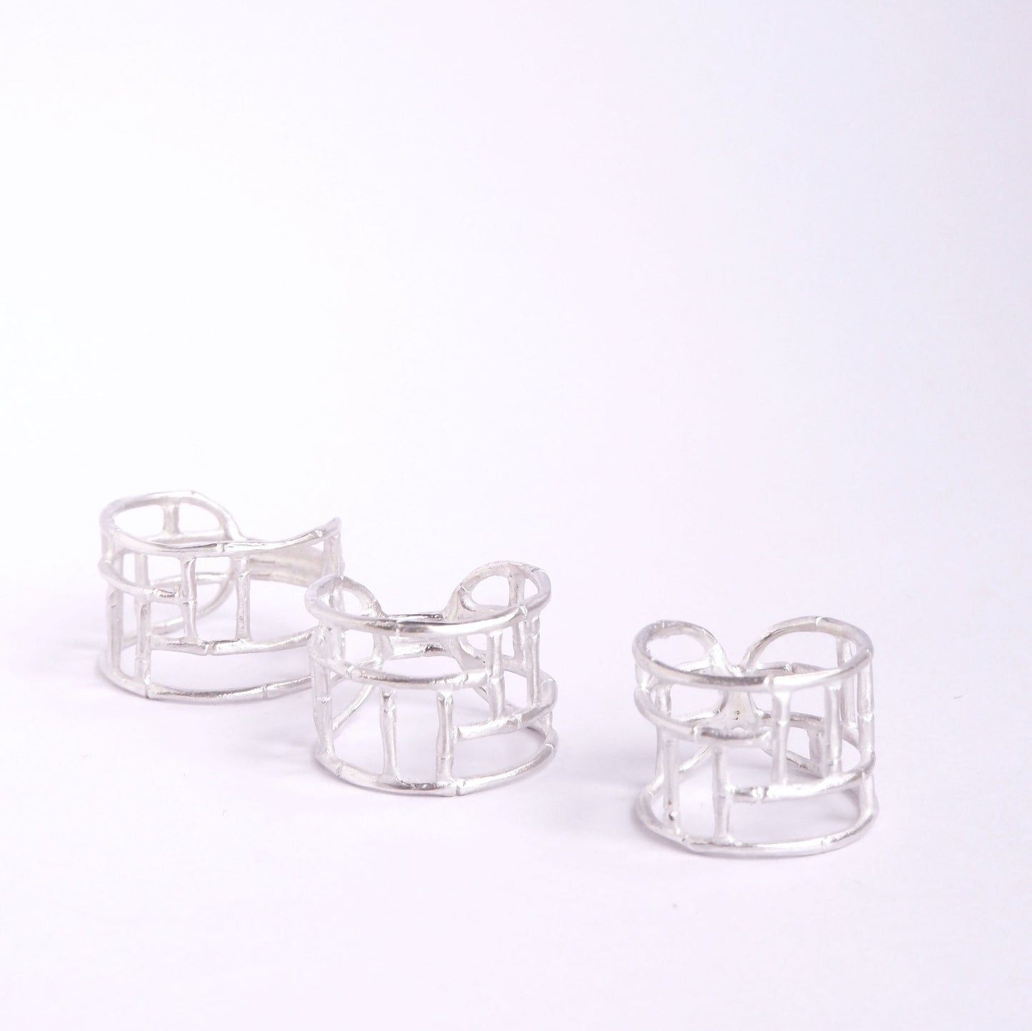 Three wide Sterling Silver rings with geometric open-work Bamboo screen design, on a white background
