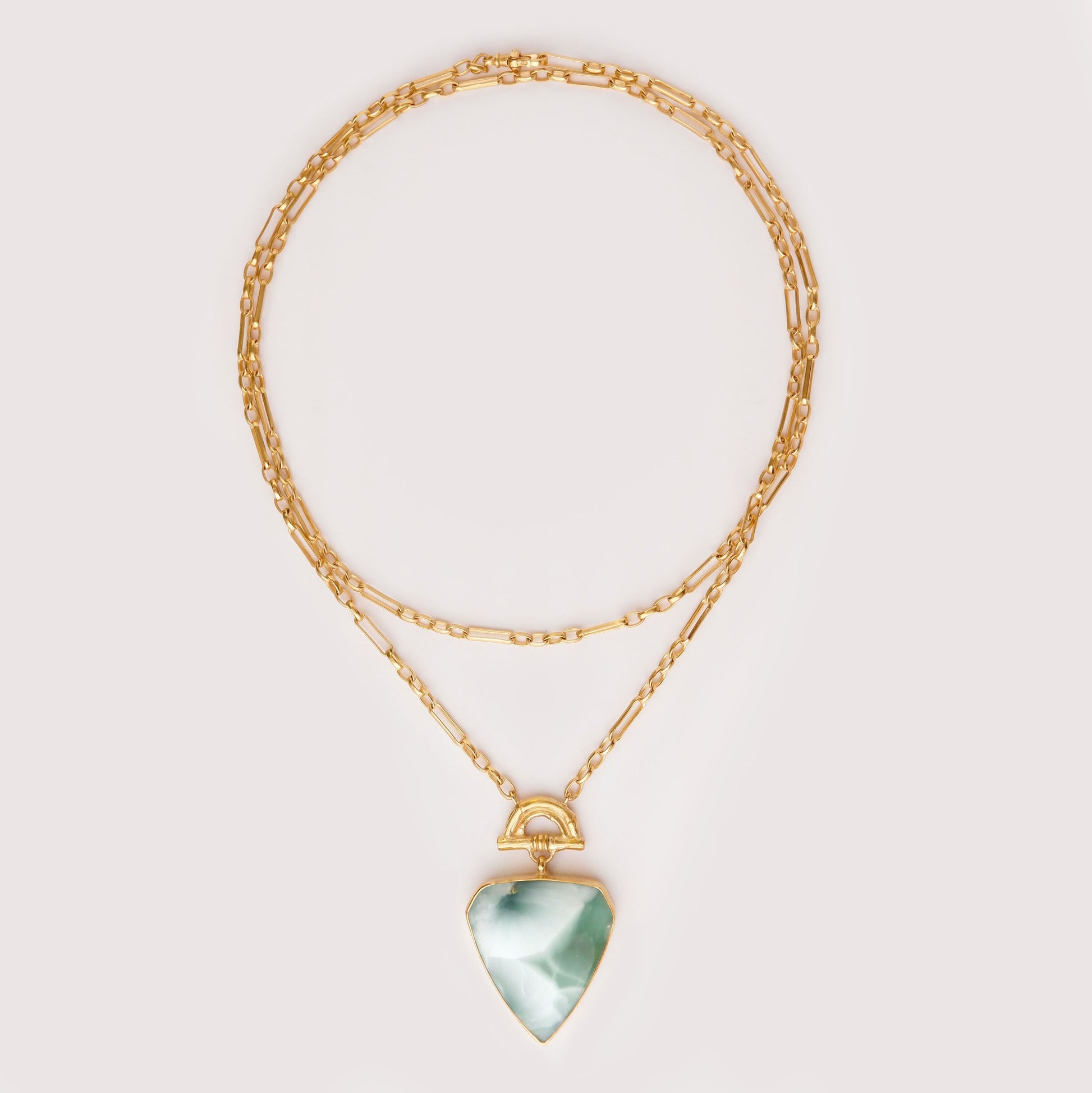 Pendant with large shield shaped green hemimorphite gemstone hanging from Gold Bamboo Arch, a long doubled gold chain. light grey Background