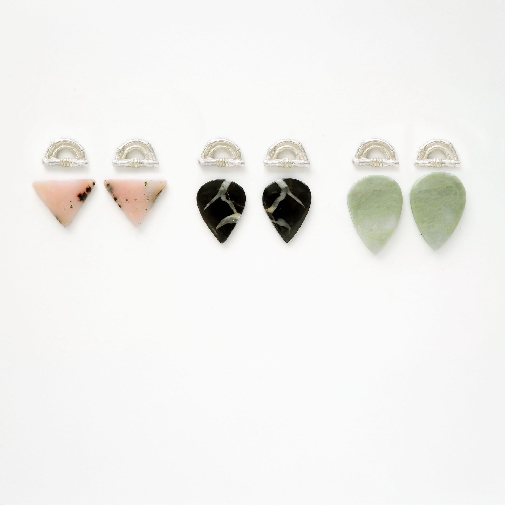 three pairs of Sterling Silver bamboo sunrise arch design pieces (earring tops) with pointed gemstone cabochons in pale pink opal, black marbled Septarian, and light green Serpentine.