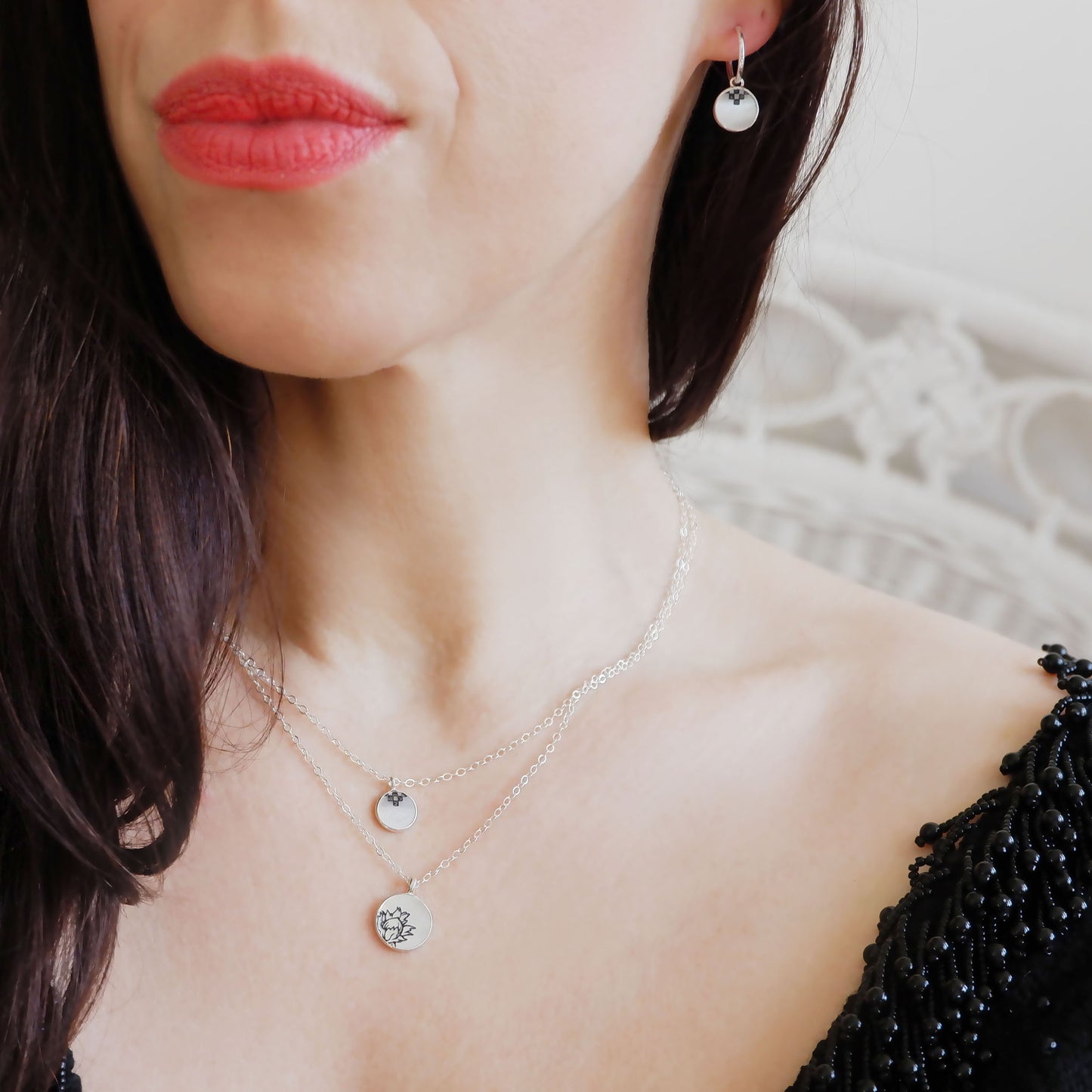 two small engraved mother of pearl pendants, in different sizes, and on different length sterling silver chain, shown on model for scale, with matching hoop earrings.