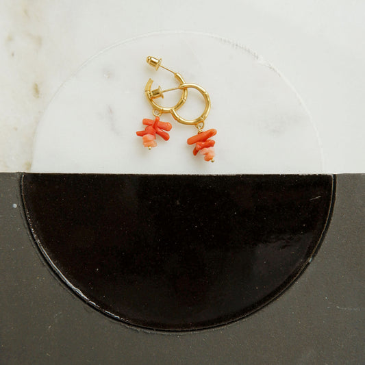 small gold bamboo hoops, with stacked coral branch bead charms, still life with marble and ceramaic tiles