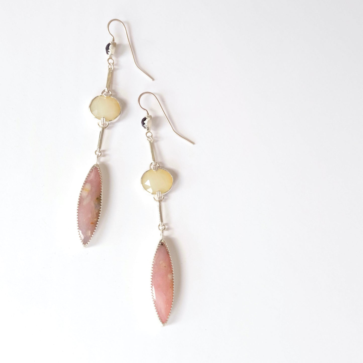 A pair of long drop earrings handcrafted in recycled Sterling Silver, featuring stunning Peruvian Pink Opal Marquise Cabochons, rare faceted butter-yellow Kenyan Opal ovals, and tiny faceted black Onyx Trillions. White background