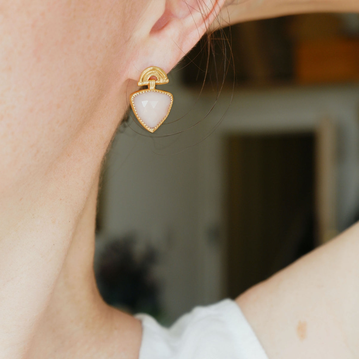 Gold Vermeil stud drop earrings , featuring triple arches of bamboo, paired with a hanging faceted Trillion shaped pale Pink Opal gemstone charm pendant, set with serrated gold teeth. Shown on model