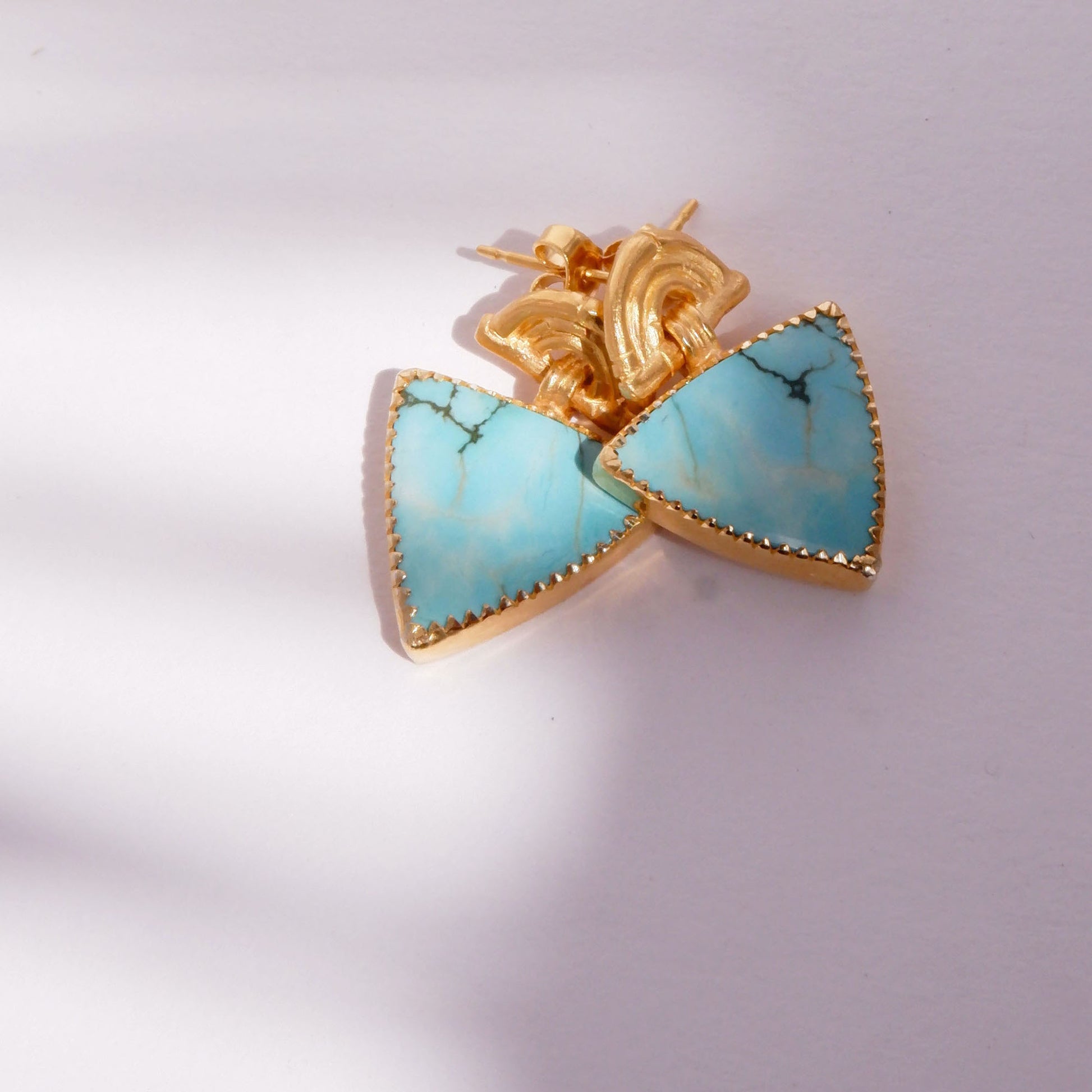 small stud earrings in gold vermeil, featuring triple arches of bamboo, hung with  triangular turquoise gemstone charm pendants, set with gold teeth.