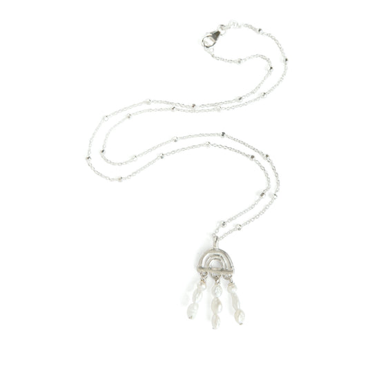 Silver  necklace featuring an arched bamboo sunrise style pendant, with fringe of freshwater seed pearls, hung from a satellite chain, with faceted beads, on a white background