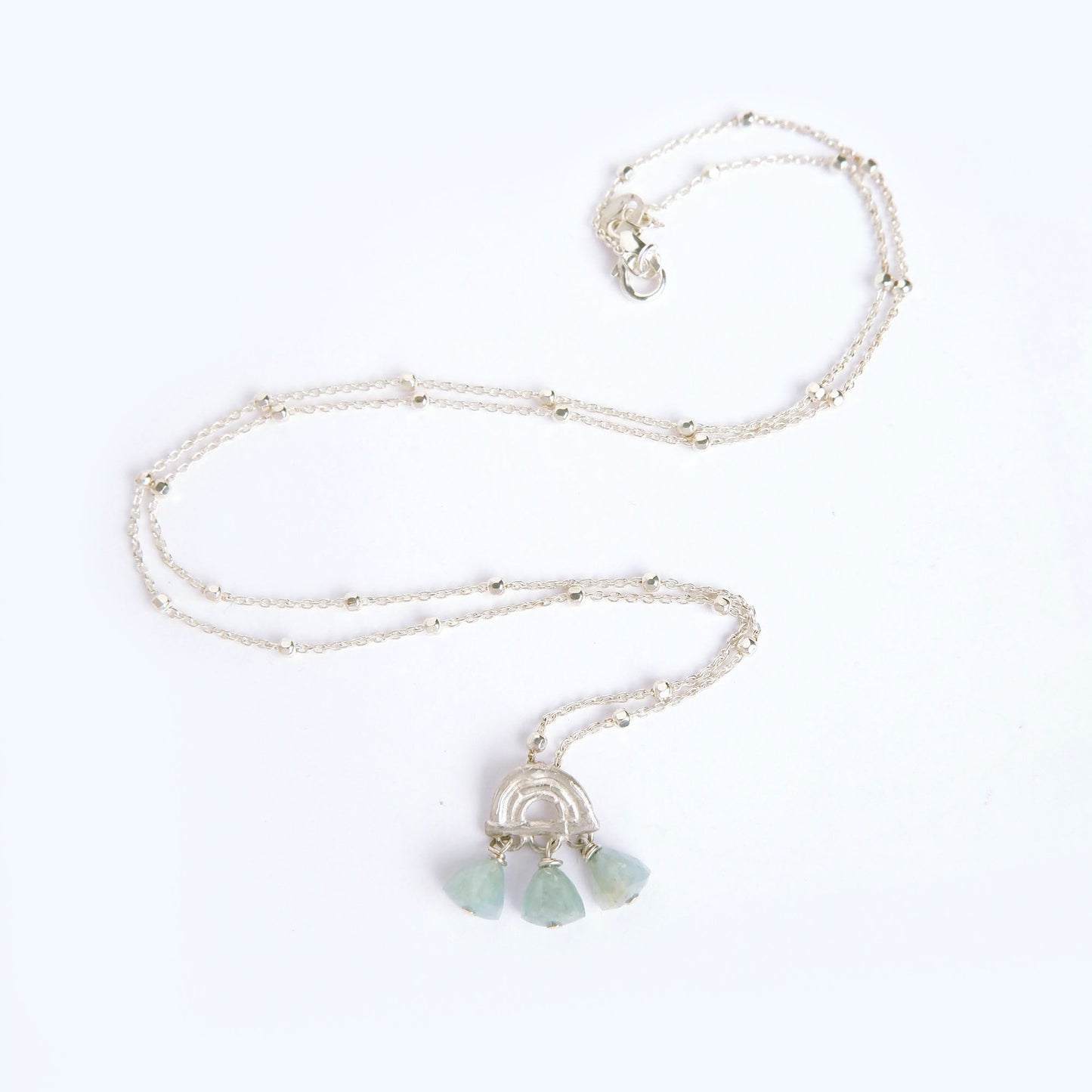 small pendant in sterling silver, featuring a triple arch of bamboo, fringed with pyramid trillion beads in aquamarine, on beaded satellite chain in sterling silver.