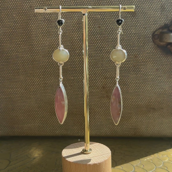 video A pair of long drop earrings handcrafted in recycled Sterling Silver, featuring stunning Peruvian Pink Opal Marquise Cabochons, rare faceted butter-yellow Kenyan Opal ovals, and tiny faceted black Onyx Trillions. brown cavas background