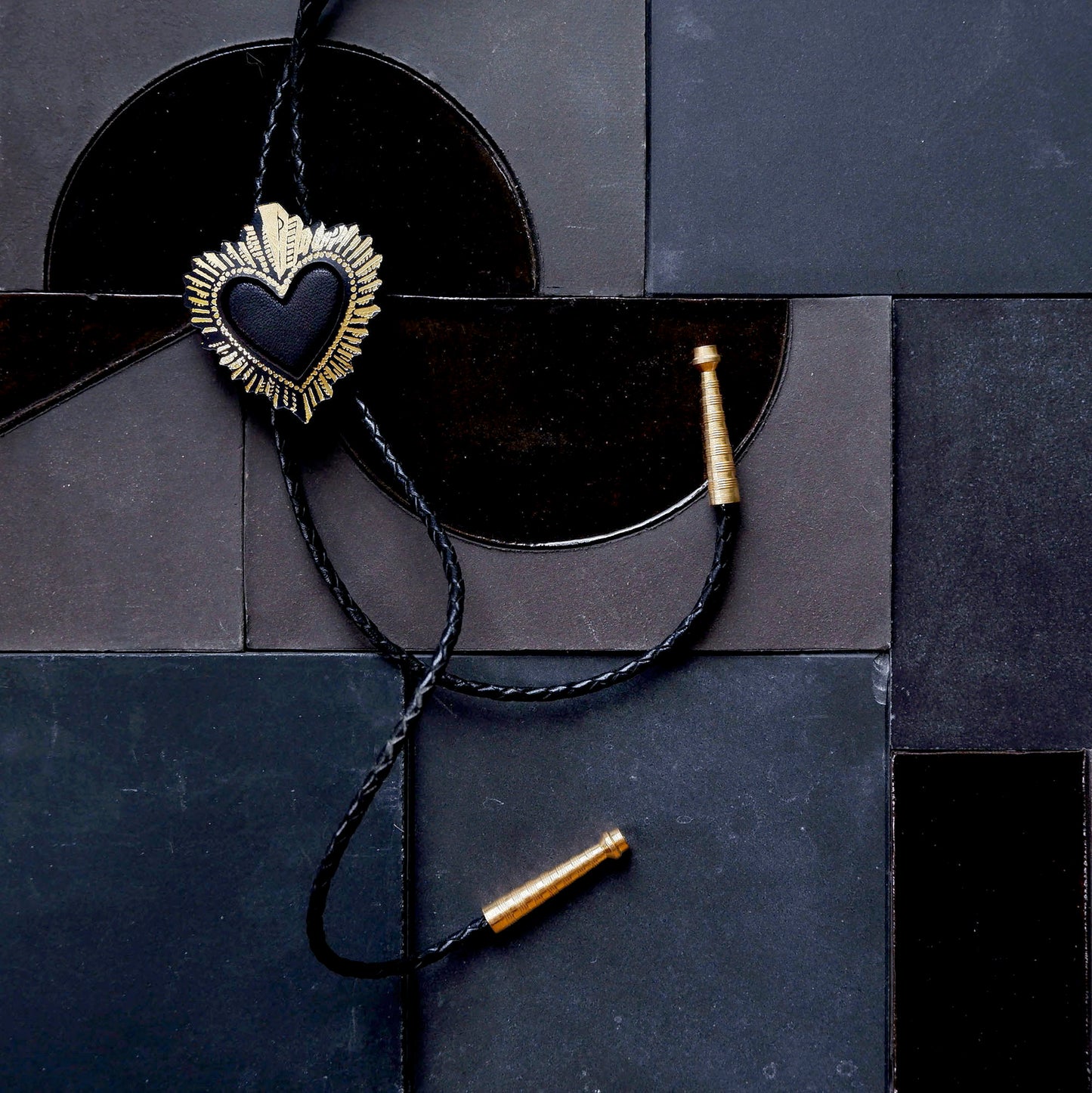 black sacred heart bolo tie on black tile background
